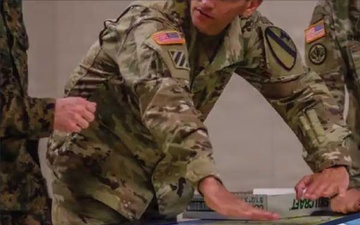 Defense Threat Reduction Agency personnel collaborate around conference tables and monitor multiple screens.