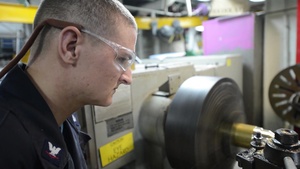 Sailor Aboard USS Essex Machines a Piece of Brass