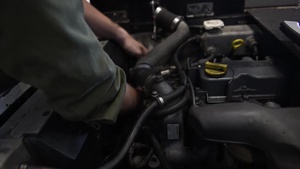 A Marine performs maintenance on a tow tractor