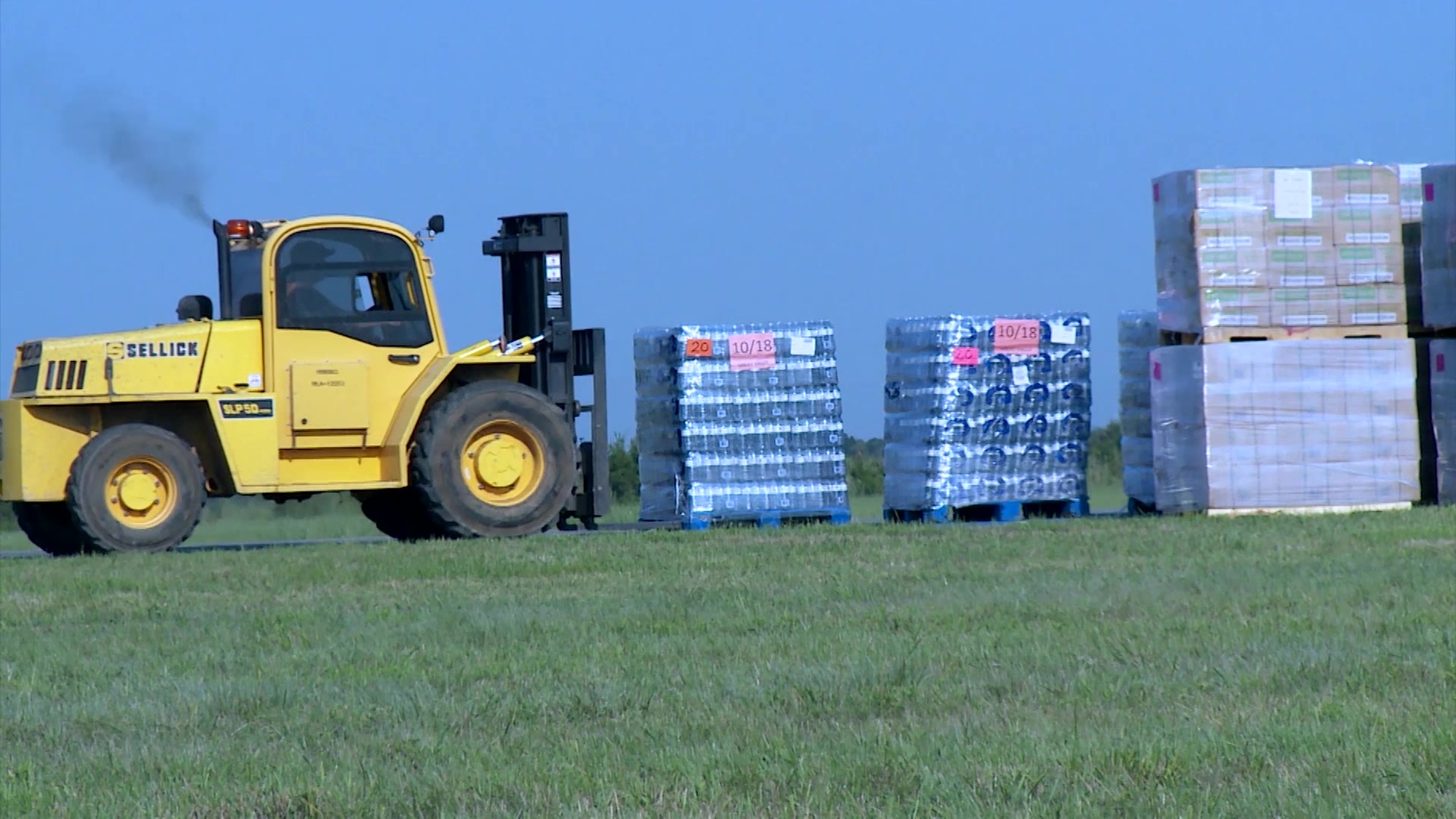 Contractors at Seguin Auxiliary Airfield work to widen a road for truckers convenience. Other contractors transport and stage food and water for pick up.