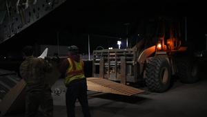 A C-17 delivers vehicles and pallets