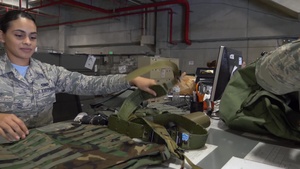 A1C Jasmine Arce sorts and passes out MOPP gear to costumer w/slate