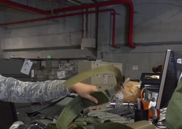 A1C Jasmine Arce sorts and passes out MOPP gear to costumer w/slate