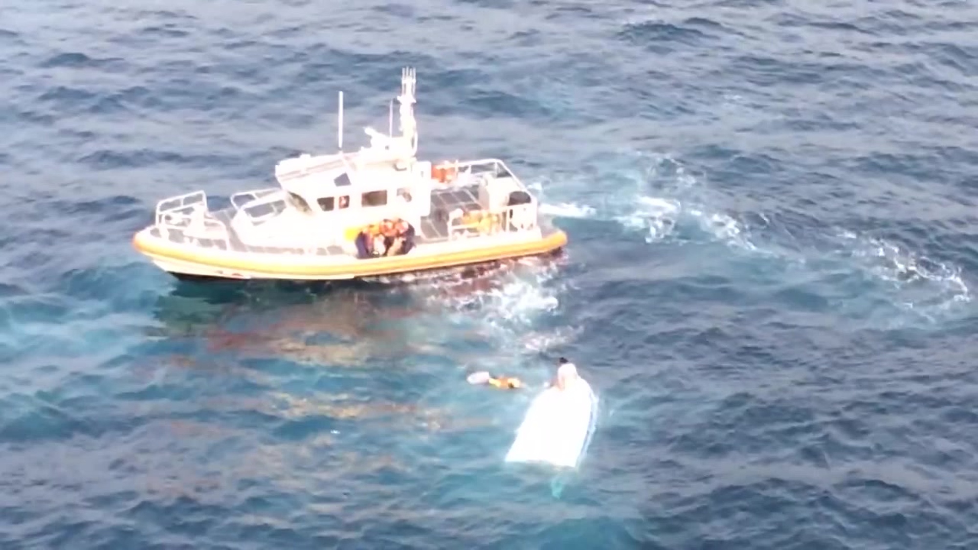 A Coast Guard Station Channel Islands Harbor boatcrew and a rescue swimmer from Coast Guard Air Station San Francisco Forward Operating Base Point Mugu assist three people from the water after their vessel capsized near Anacapa Island, California, June 22, 2018. The three people in the water were transported to Station Channel Islands were emergency medical services awaited. (U.S. Coast Guard Video)