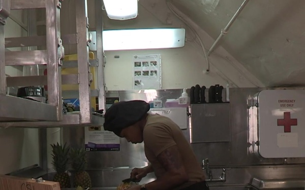 U.S. Navy Culinary Specialist Seaman Chris Brown, from Seattle, carves fruit