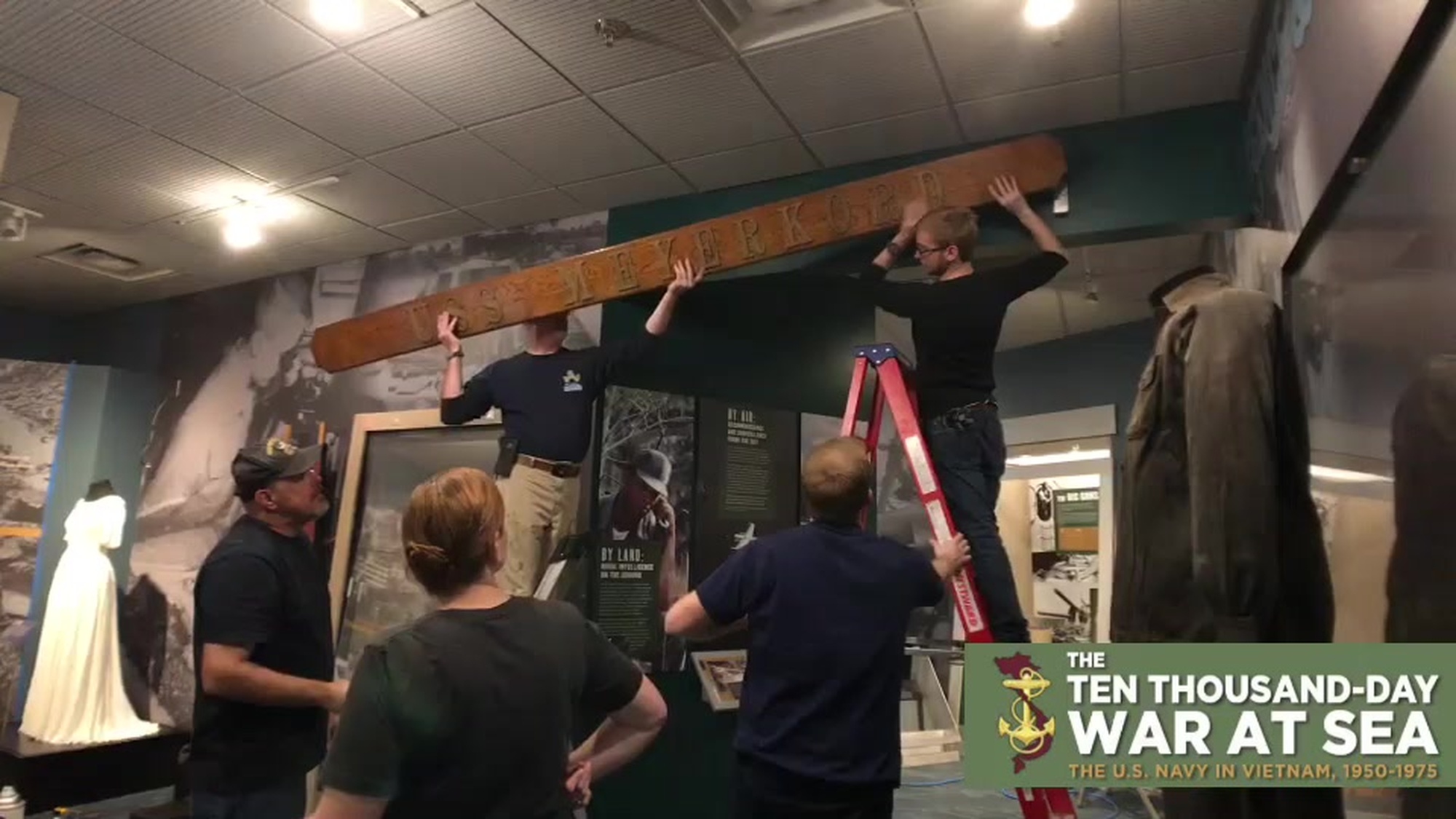 B-roll footage without sound of staff members with the Hampton Roads Naval Museum hanging a name board from the Knox-Class Frigate USS Meyerkord (FF-1058) in their gallery. The frigate bears the namesake of Navy Cross recipient Lieutenant Harold Dale Meyerkord, who perished in South Vietnam on March 16, 1965.  The name board, and over 130 artifacts are part of a new immersive exhibit, “The Ten Thousand-Day War at Sea: The U.S. Navy in Vietnam, 1950-1975,” which is set to open on October 9, 2019 at 10am. (US Navy Video by Max Lonzanida/Released).
