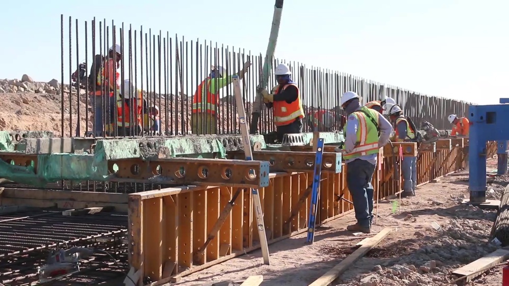 DVIDS Video Workers pour concrete into a footer mold for a barrier