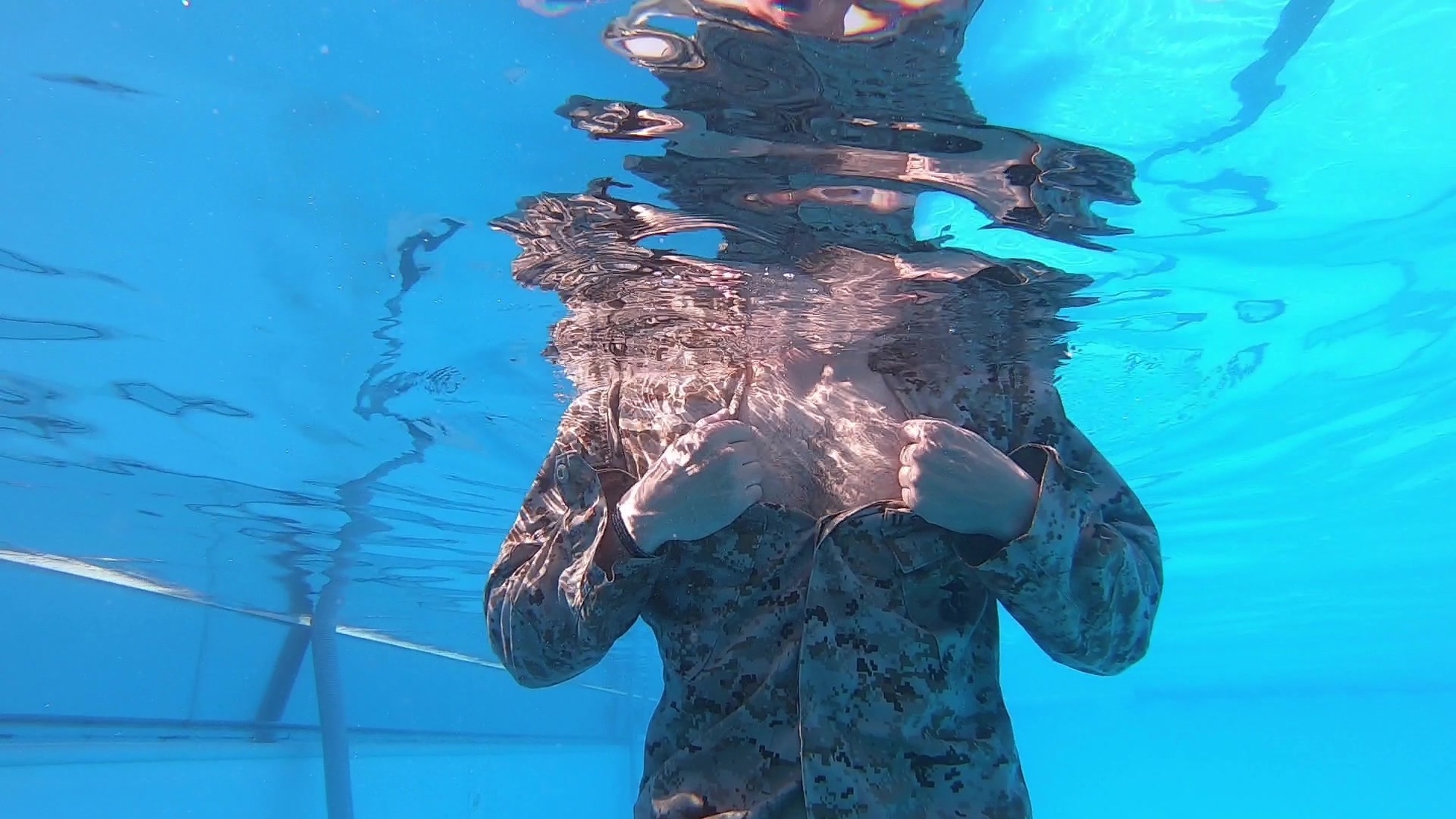 Given an aquatic environment with deep water, while wearing a combat uniform.
o	Keep the sleeves buttoned and the top two front buttons unbuttoned.
o	Grasp the collars, press down with your thumbs where the rank insignia is normally pinned, and pull the collar down tight against your neck, creating a seal. 
o	Hold the grasped fingers firmly against the chest.
o	Take a deep breath and bend forward no more than 45 degrees to prevent the air from escaping through the back of the blouse.
o	Turn your head to either side and break the seal of your collar. Bury your face as far in your armpit as possible and forcefully exhale a full lung of air into the blouse.
o	Immediately reseal the collar. Tilt your head back and raise your elbows to allow air to create a floating cushion around the back of the neck. Cross your ankles and stop  moving.