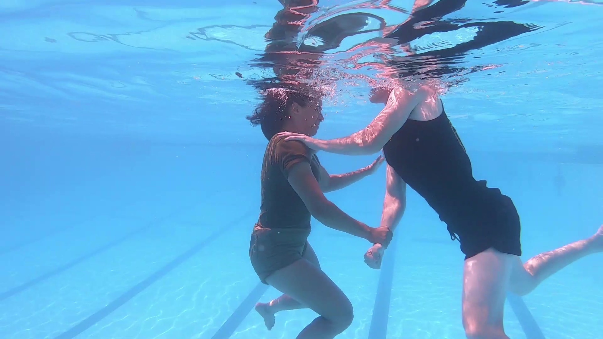The wrist-escape is used when a victim grabs the rescuer on the arm or wrist. Submerge the victim quickly by reaching across with the free hand, pushing down on the victim’s shoulder to submerge the victim and kicking to propel upward. While keeping the victim submerged with the hand on the victim’s shoulder, give three hard jerking pulls with the trapped hand in order to attempt to break free from the victim’s grasp. Once free, swim away of the victim.