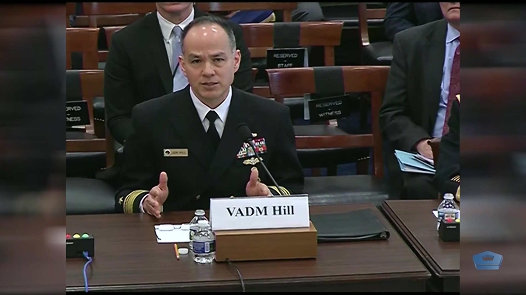 A Navy vice admiral speaks at a table. 