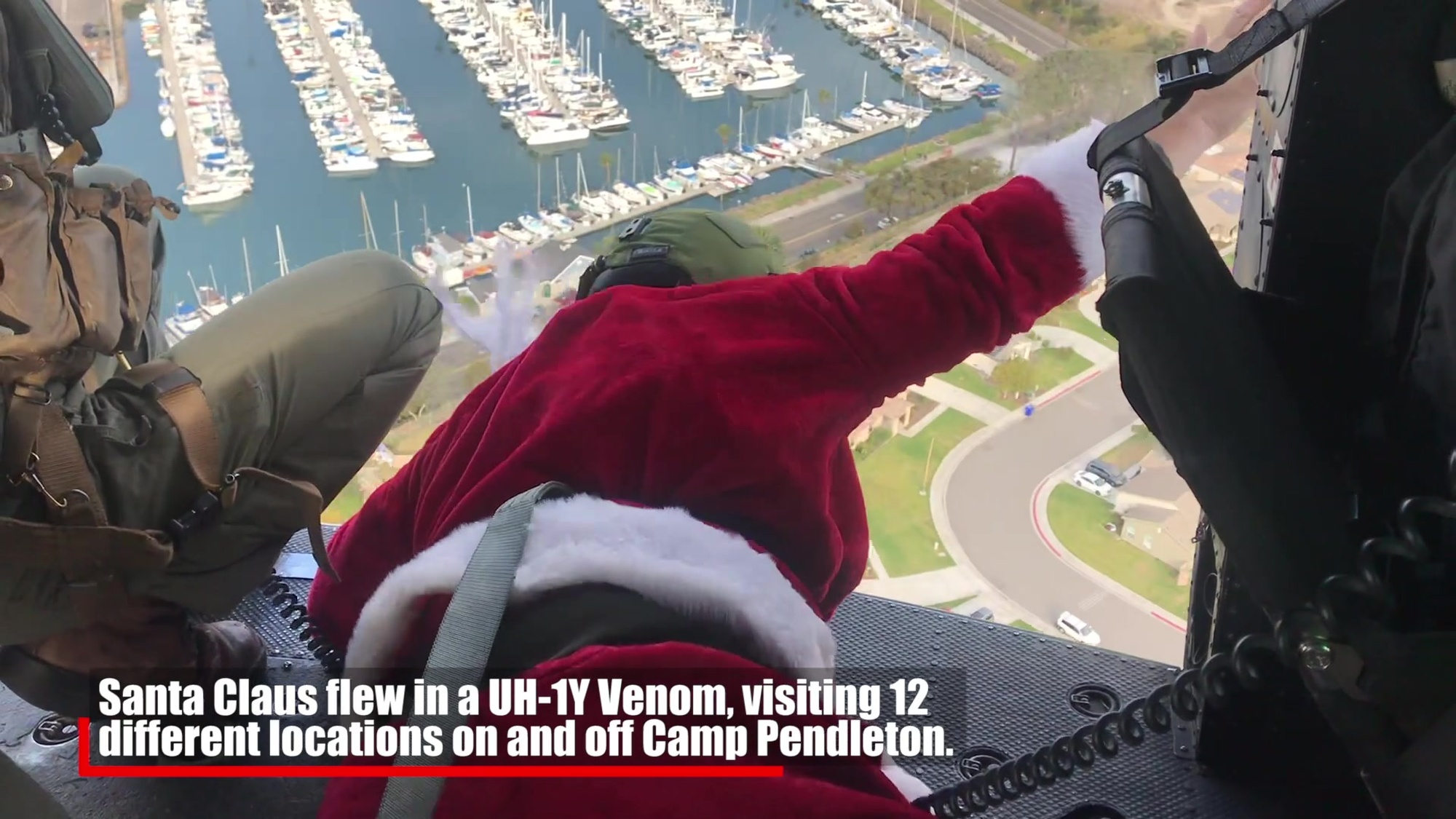U.S. Marine Sgt. William Hinkle, an aerial observer with Marine Light Attack Helicopter Training Squadron 303, Marine Aircraft Group 39, 3rd Marine Aircraft Wing, waves to families while dressed as Santa Claus as he flies over a neighborhood outside of Marine Corps Base Camp Pendleton, California, in a UH-1Y Venom helicopter, Dec. 5, 2020. Since efforts to mitigate the spread of COVID-19 have impacted holiday plans for many living in Southern California, HMLAT-303 wanted to bring Santa Claus to families living on base and the surrounding area to spread holiday cheer. Hinkle is a native of Parachute, Colorado.