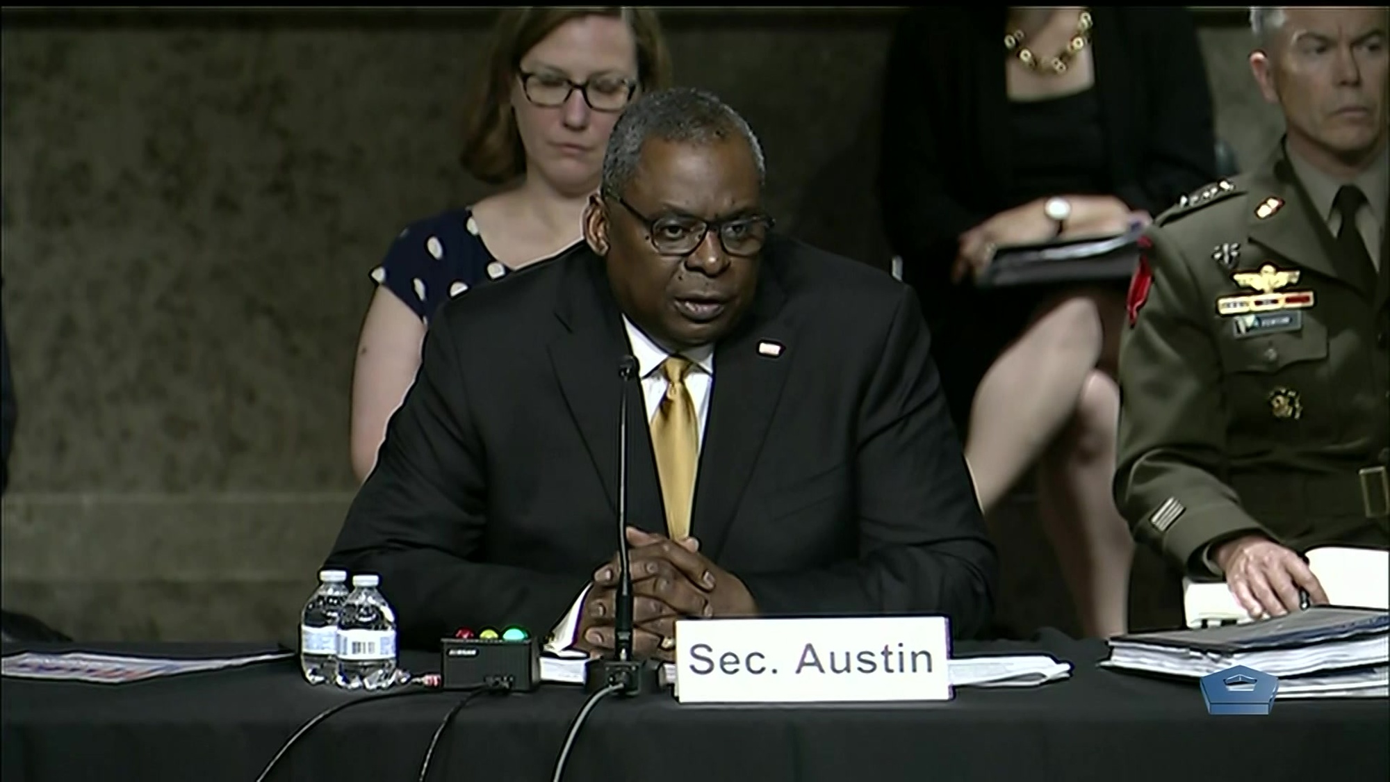 Secretary of Defense Lloyd J. Austin III sits and speaks at a table.