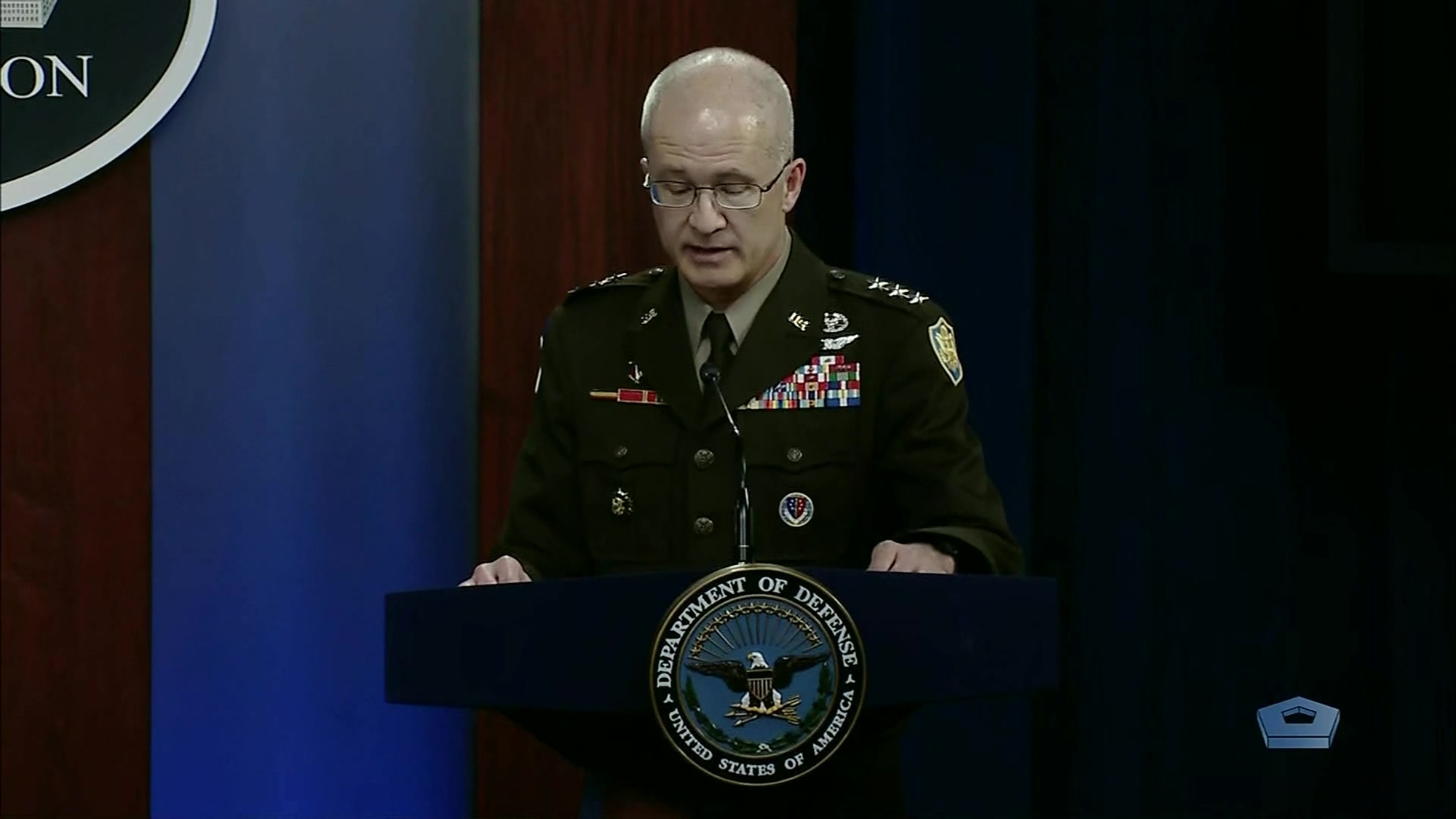 A military official speaks at a lectern.
