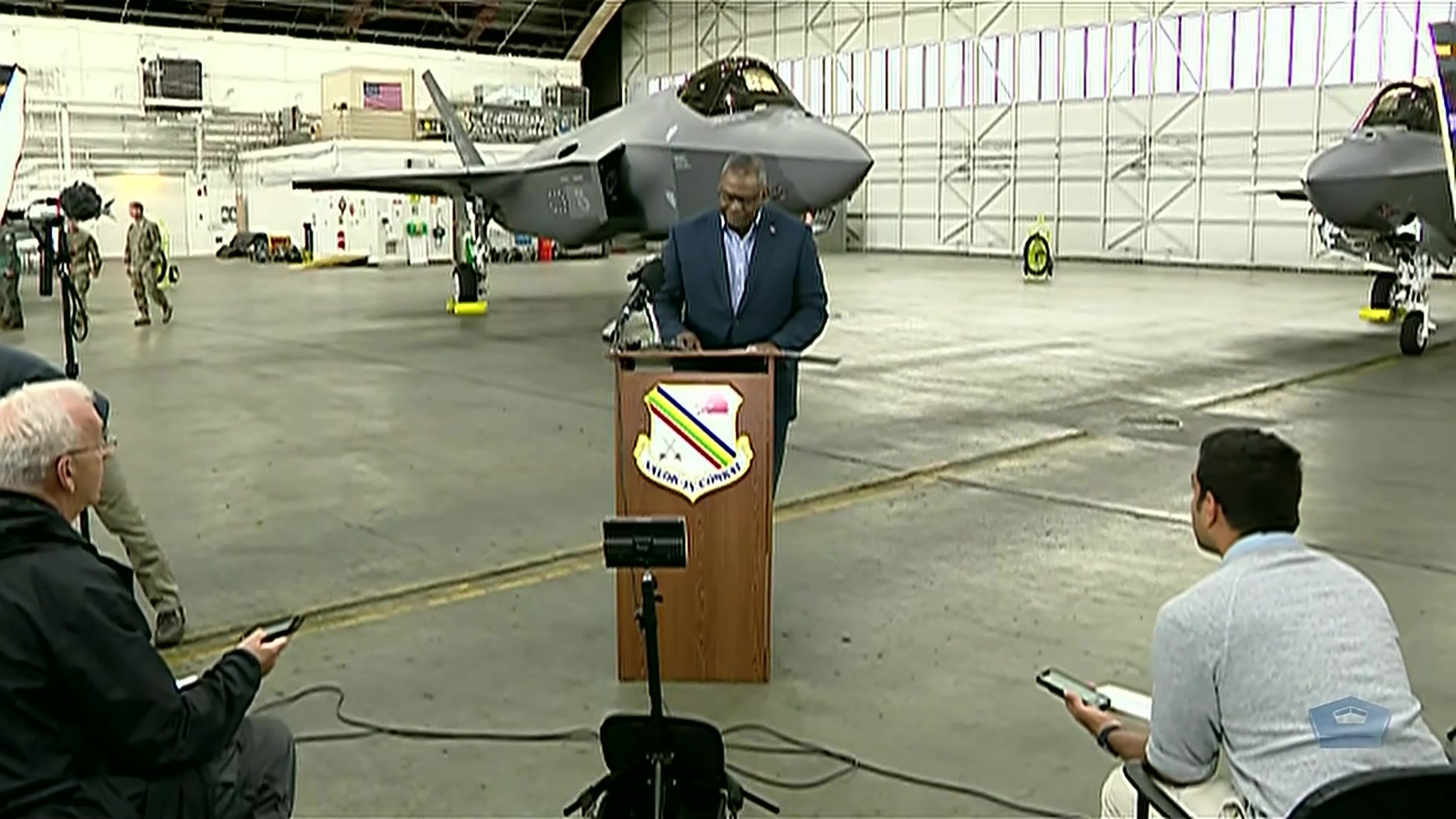 Secretary of Defense Lloyd J. Austin III stands and speaks in front of aircraft in hangar. 
 
