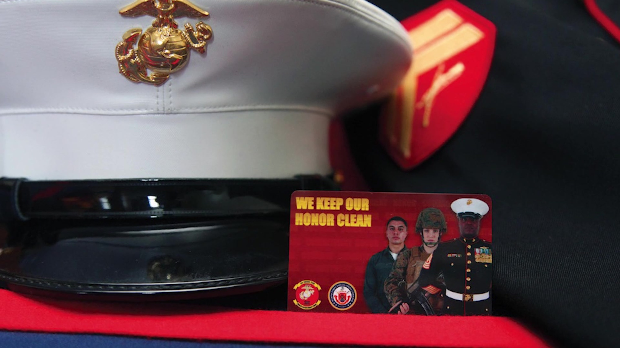 Image of a display that includes a Marine cover, jacket and a card depicting Marines.