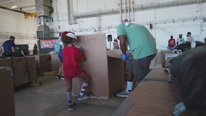 Volunteers pack donated goods into airdrop bundles during the 70th annual Operation Christmas Drop