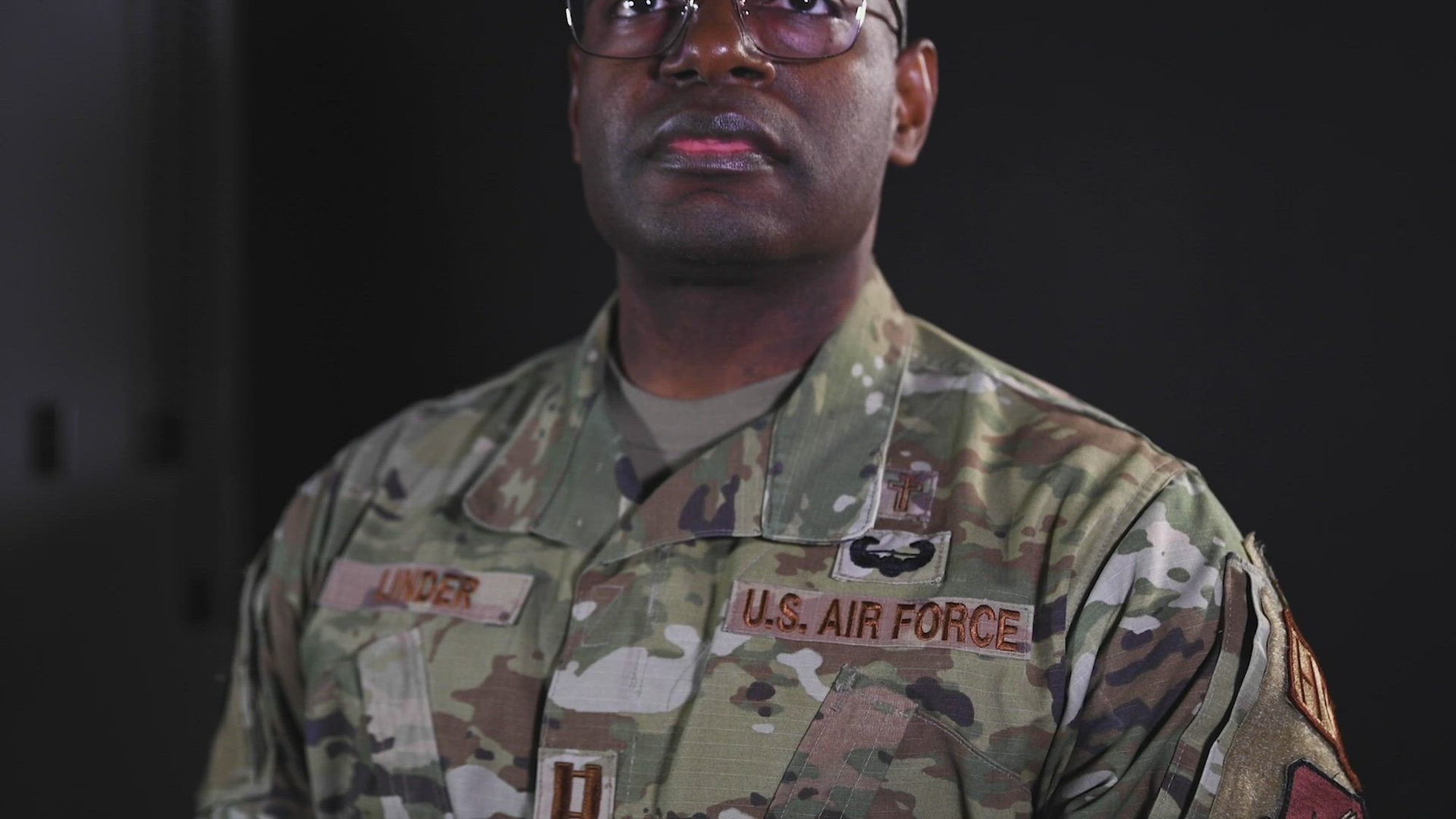 Airman in uniform against a black background.