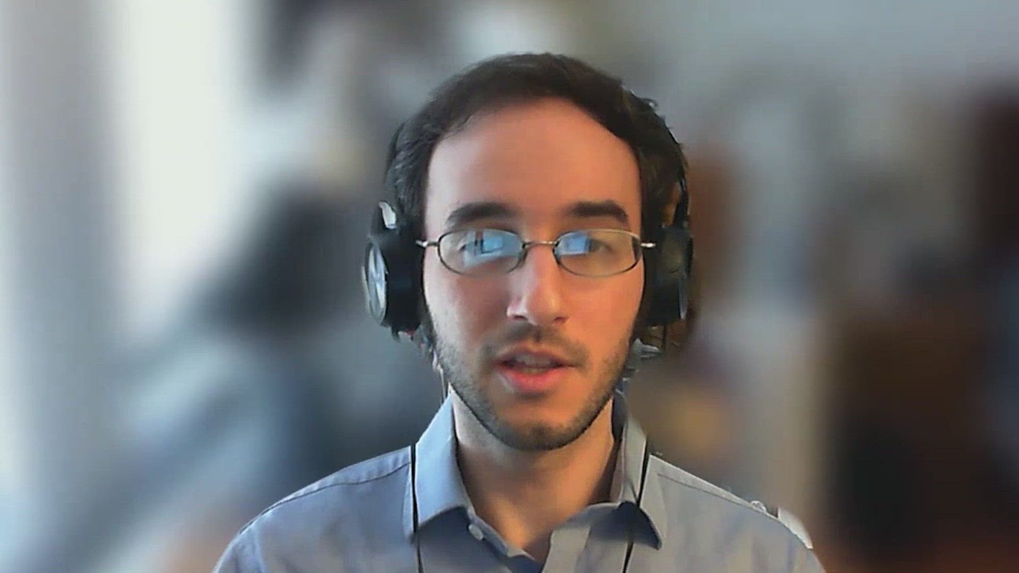 A person wearing headphones speaks to a camera.