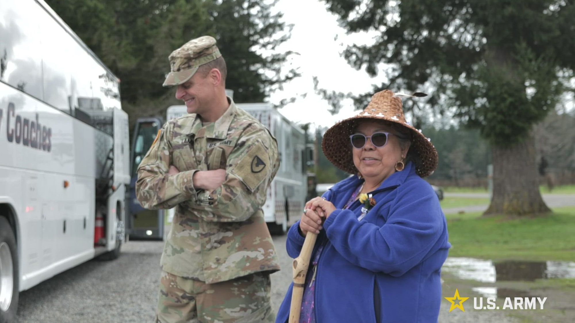 A service member and civilian smile while standing together outdoors.