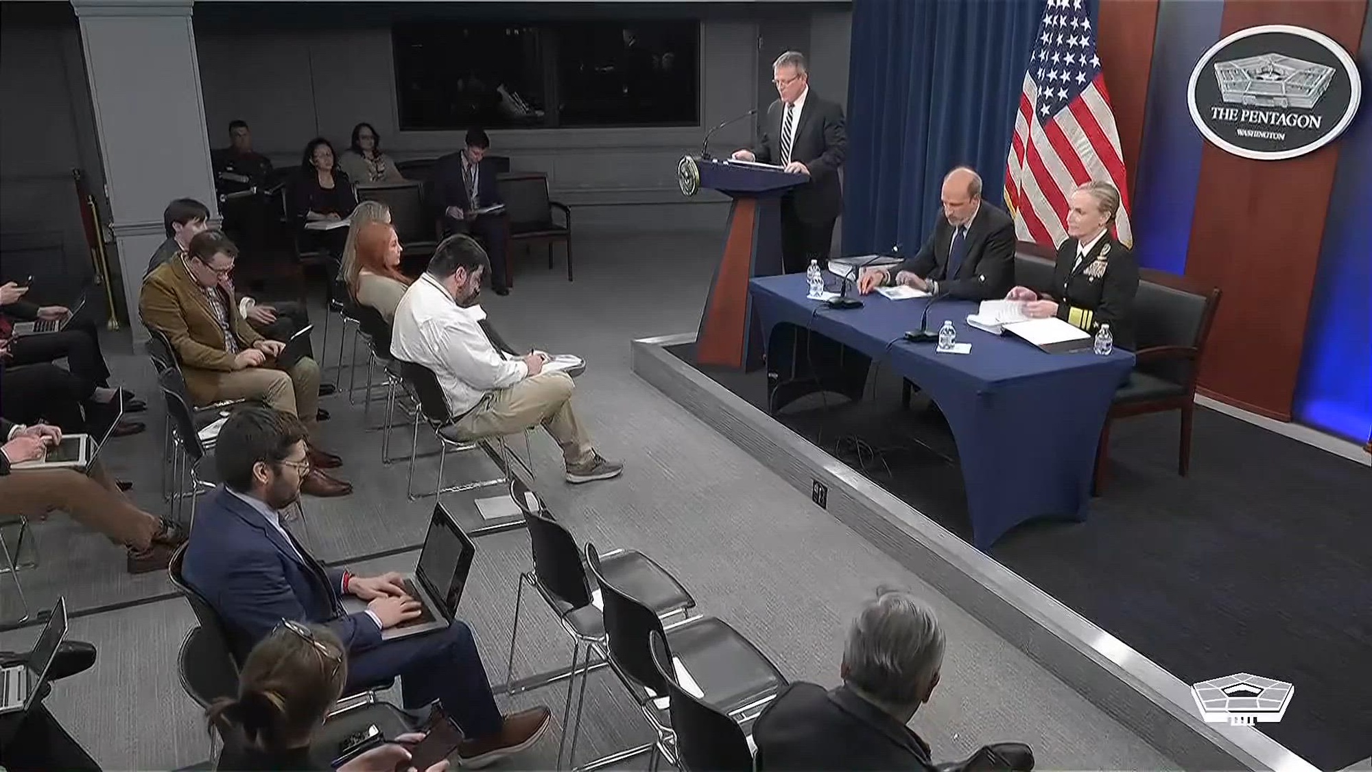 Undersecretary of Defense Comptroller and Chief Financial Officer and Joint Staff Director of Force Structure, Resources and Assessment sit at a briefing table with reporters in chairs facing them.