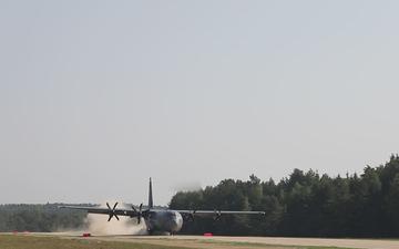 C-130 delivers combat supplies on dirt runway.