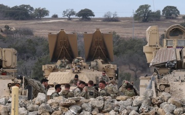 M2A3 Bradley Fighting Vehicle and Boeing AH-64 Apache Attack Helicopter engages targets during 3ABCT/1CD CALFEX ×