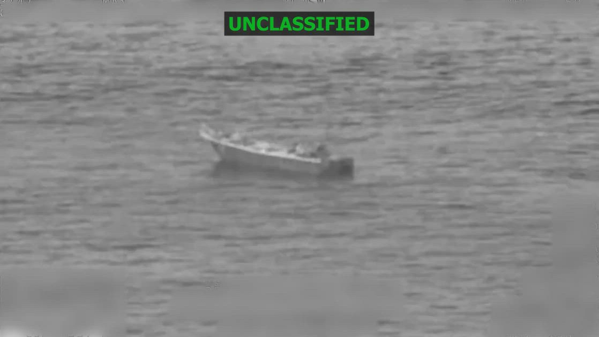 Black and white overhead footage of a boat in the water.