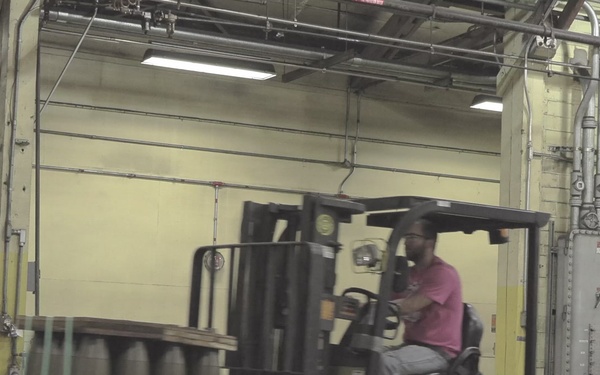 Iowa Army Ammunition Plant employee moving 155mm/M795 projectile rounds.