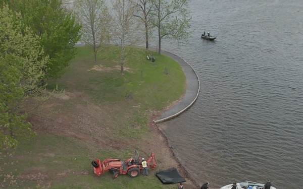Volunteers and U.S. Army Corps of Engineers staff remove debris from the shoreline of Raystown Lake