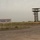The image shows the entrance area of Hawler International Airport, located in Erbil (Hawler), the capital of the Kurdistan Region of Iraq. A bilingual sign displays the airport name in both Kurdish (Sorani script) and English. The scene appears to be from an early or transitional period of the airport's development, with sparse infrastructure and construction activity visible.