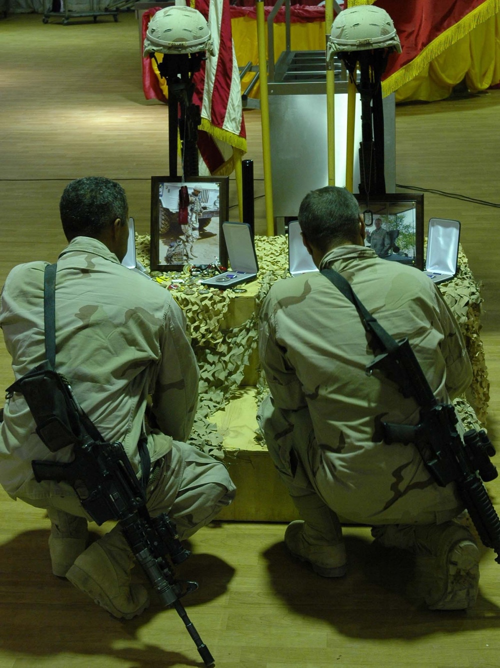 Two soldiers kneel at memorial