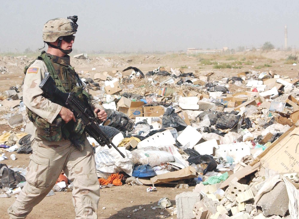 Trash litters the ground where an Oregon Guardsman walks