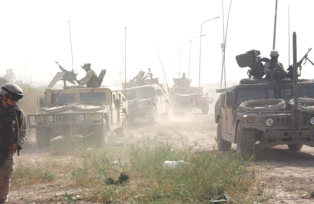 Vehicles follow Soldiers through a field