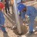 Two local workers pour concrete into a hole
