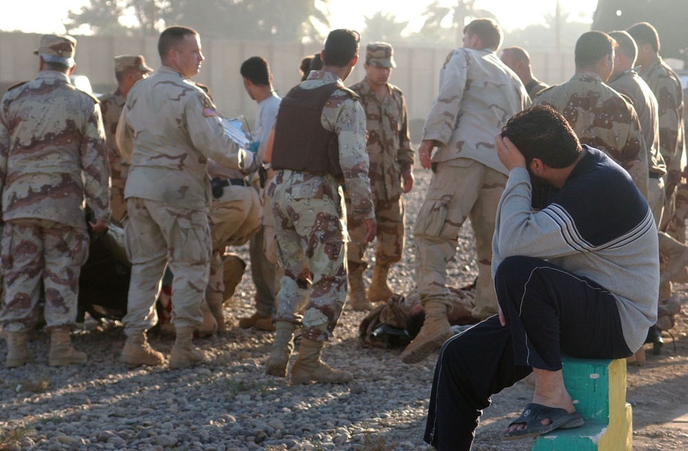 An ING looks on as his comrades are treated