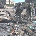 Soldiers survey a trash-filled eastern Baghdad field