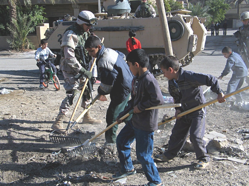 Children and Soldiers clean a field in eastern Baghdad
