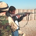 An Iraqi police officer aims his AK-47 rifle