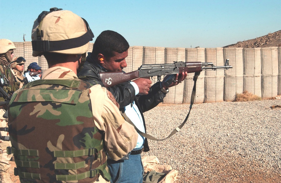 An Iraqi police officer aims his AK-47 rifle