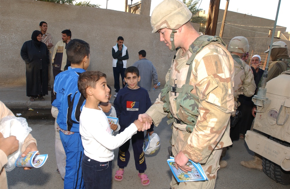 PFC Bailey hands activity books to local children