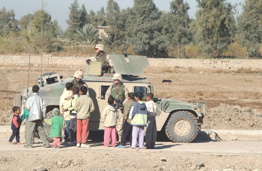 Soldiers entertain some kids near a construction site