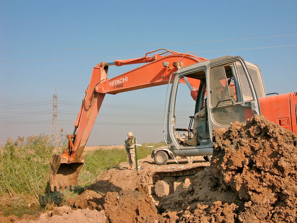 An engineer uses an excavator to bury a drainage pipe