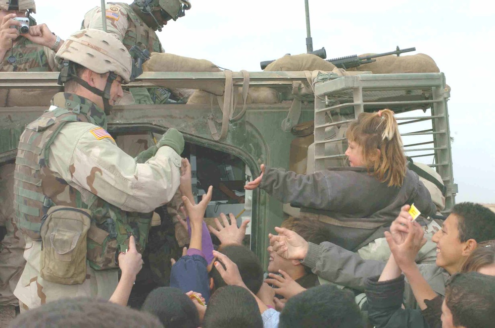 Soldiers hand out candy and school supplies to village children