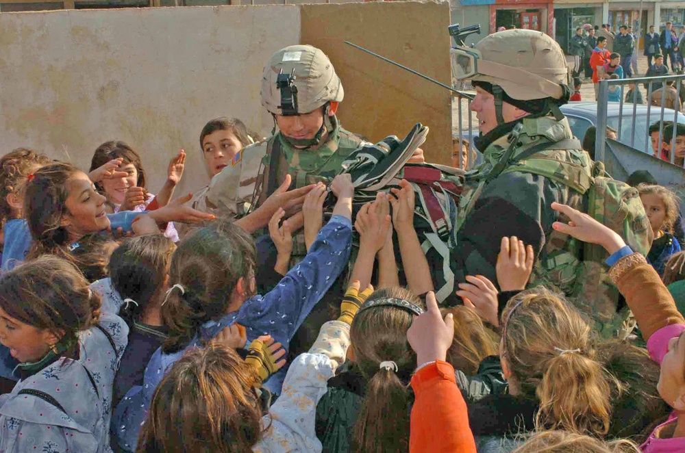 Soldiers hand out backpacks to Iraqi schoolchildren
