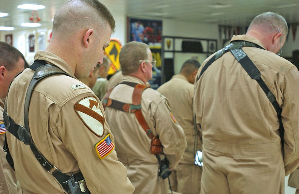 Troopers bow their heads in a moment of prayer