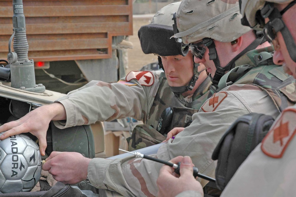 Three Soldiers air up the soccer balls for distribution