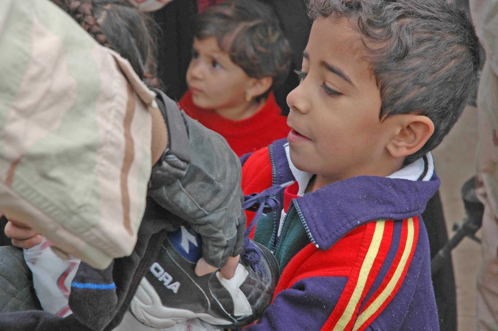 A child receives an armful of clothing and shoes