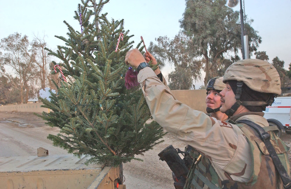 Soldiers places candy canes on a real Christmas tree