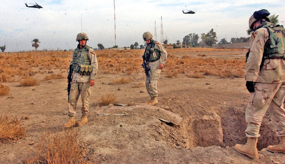 Soldiers inspect a cavity that was dug into the ground