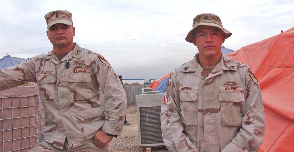 Two soldiers relax outside their tent city at Camp Striker
